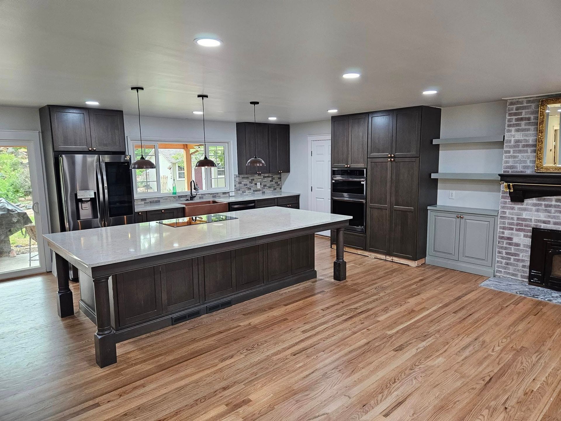 Gray kitchen cabinetry with glass-paneled upper cabinets, a granite countertop, and a coffee machine.