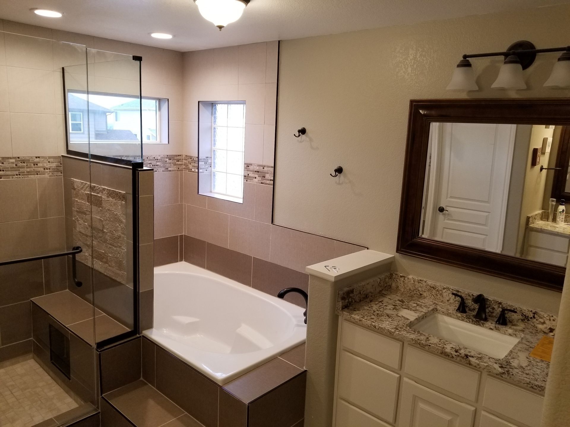 Modern bathroom with tiled walls, a soaking tub, glass shower, and vanity.