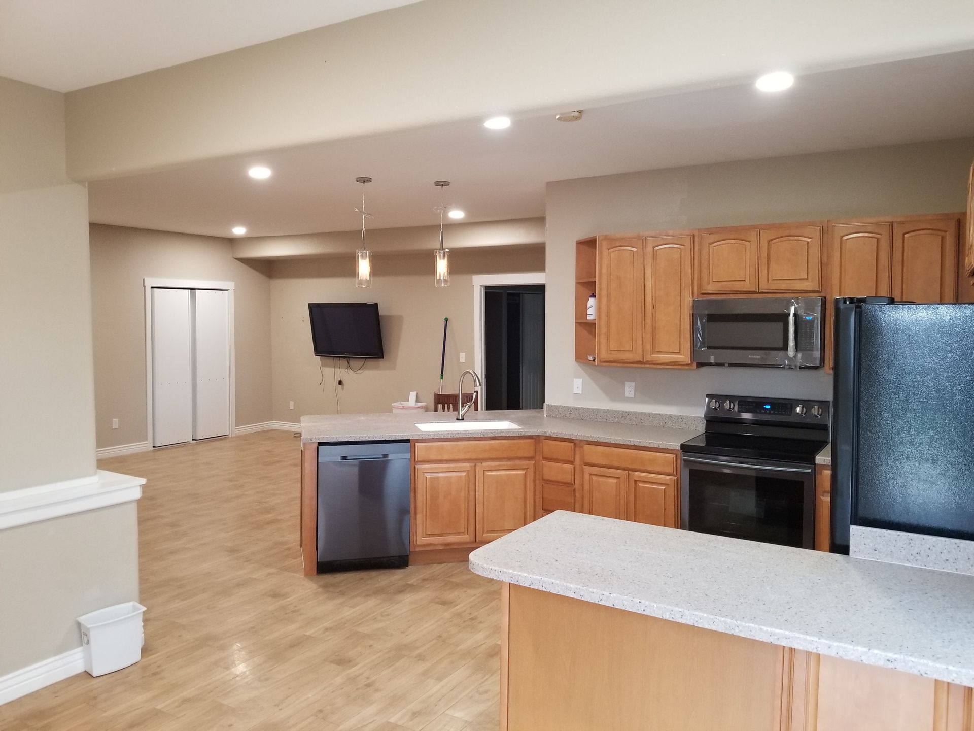 A basement kitchen with wood cabinets, stainless steel appliances, and a light-colored countertop.