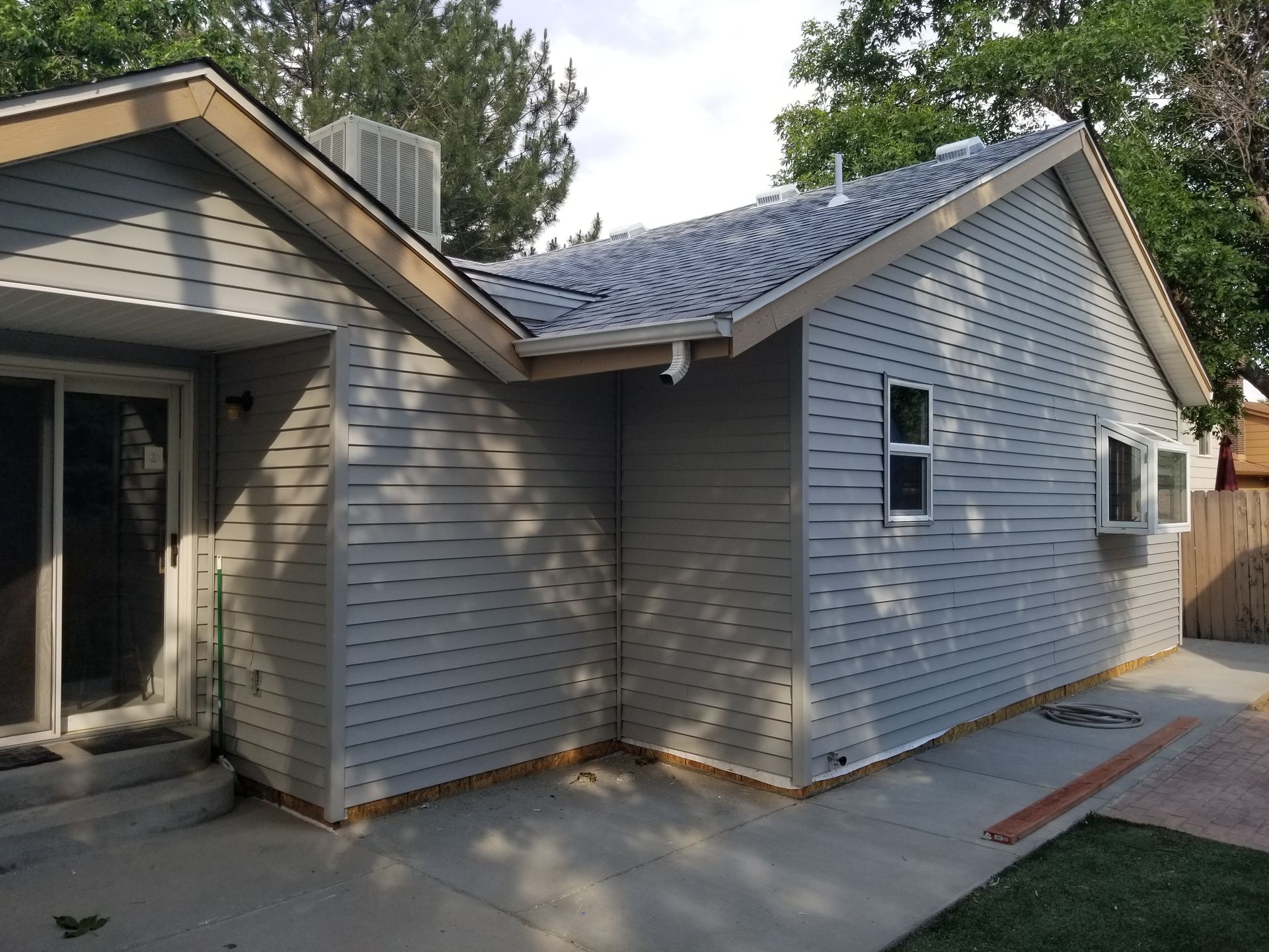 Two-story tan and brick building with a balcony and small garden on a corner lot.