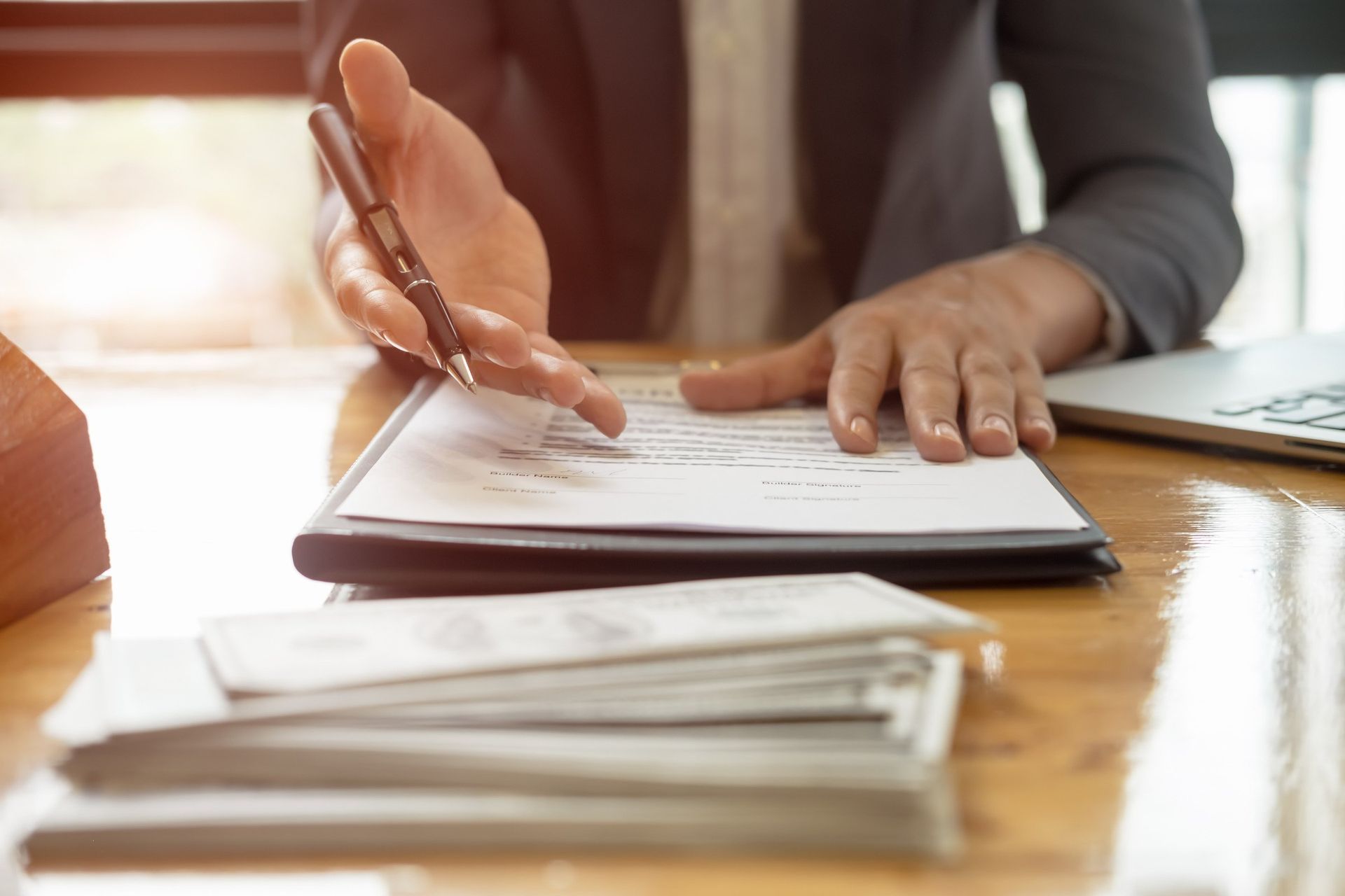 A woman is sitting at a desk holding a pen and pointing at a piece of paper.