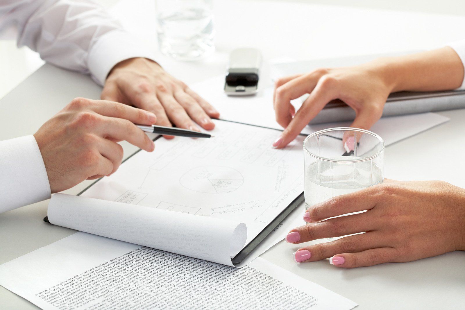 A man and a woman are sitting at a table looking at a tablet