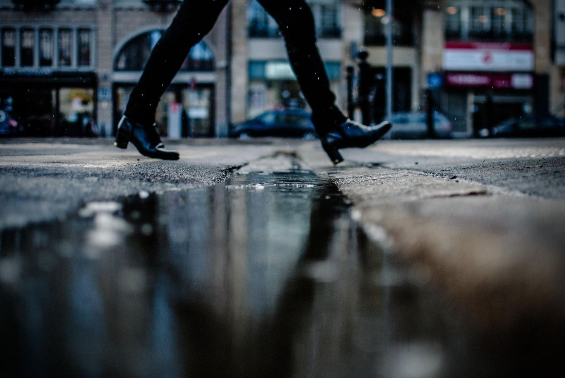 A person is walking through a puddle on a wet street.
