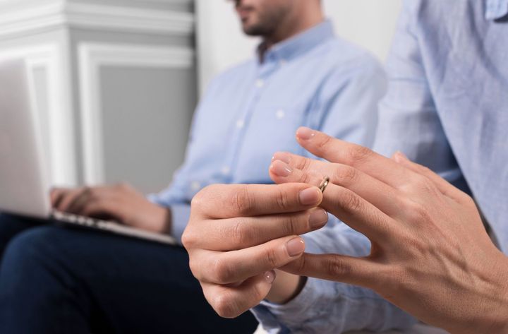 A man is holding a wedding ring on his finger.