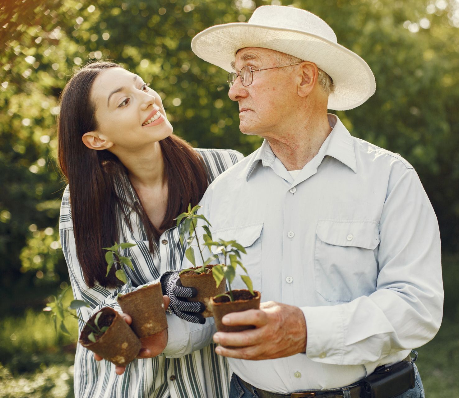 A man and a woman are holding potted plants in their hands.