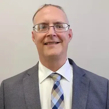 A man in a suit and tie is smiling for the camera.