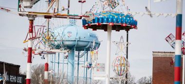 A roller coaster is sitting on top of a water tower at an amusement park.