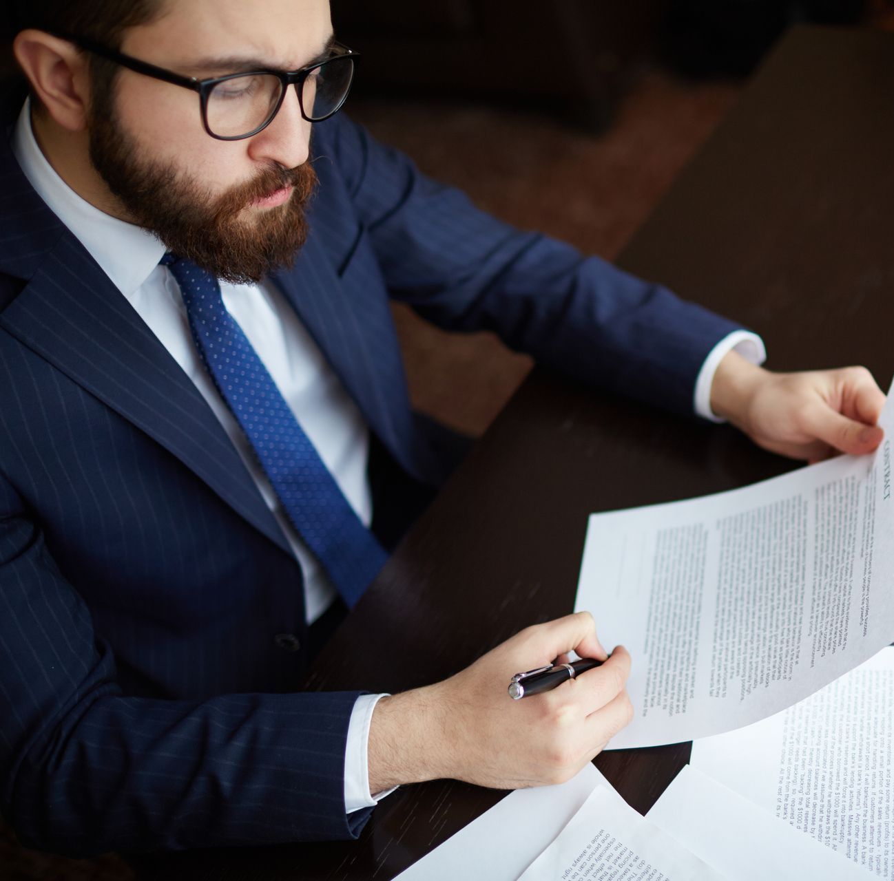 A man in a suit and tie is writing on a piece of paper