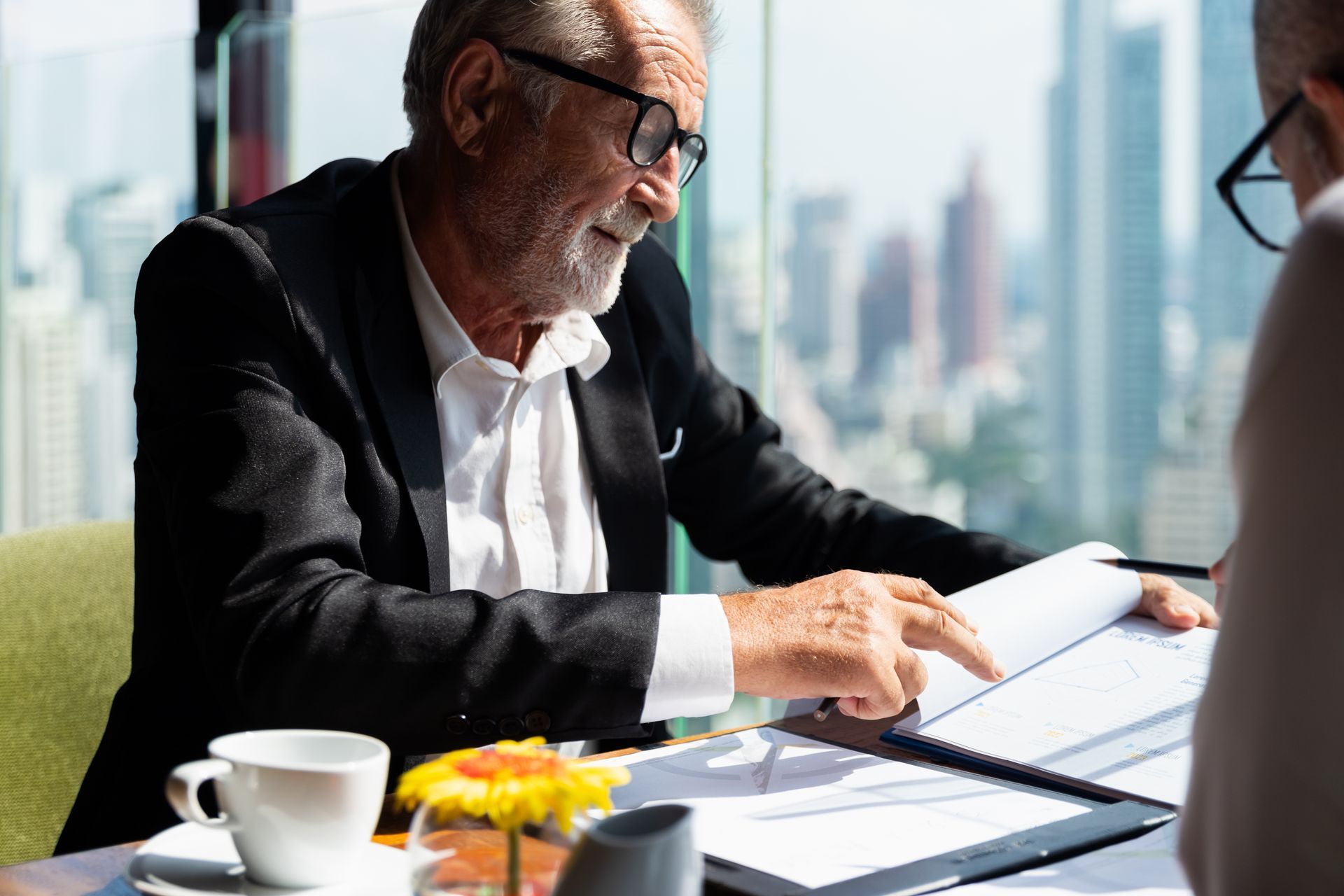 An older man is sitting at a table looking at a clipboard.