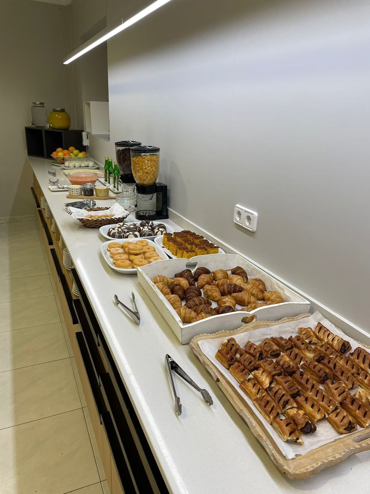 A hotel lounge area filled with vibrant, colorful upholstered armchairs and small side tables by large windows.