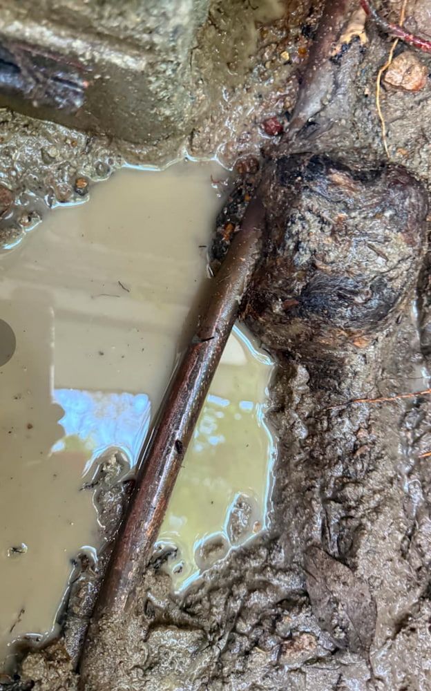 A Close Up of a Pipe in a Puddle of Mud — Around Town Plumbing Services in Canberra, ACT