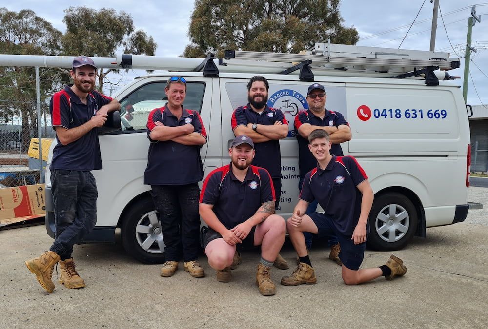 A Group of Men Are Posing for a Picture in Front of a Van — Around Town Plumbing Services in Canberra, ACT