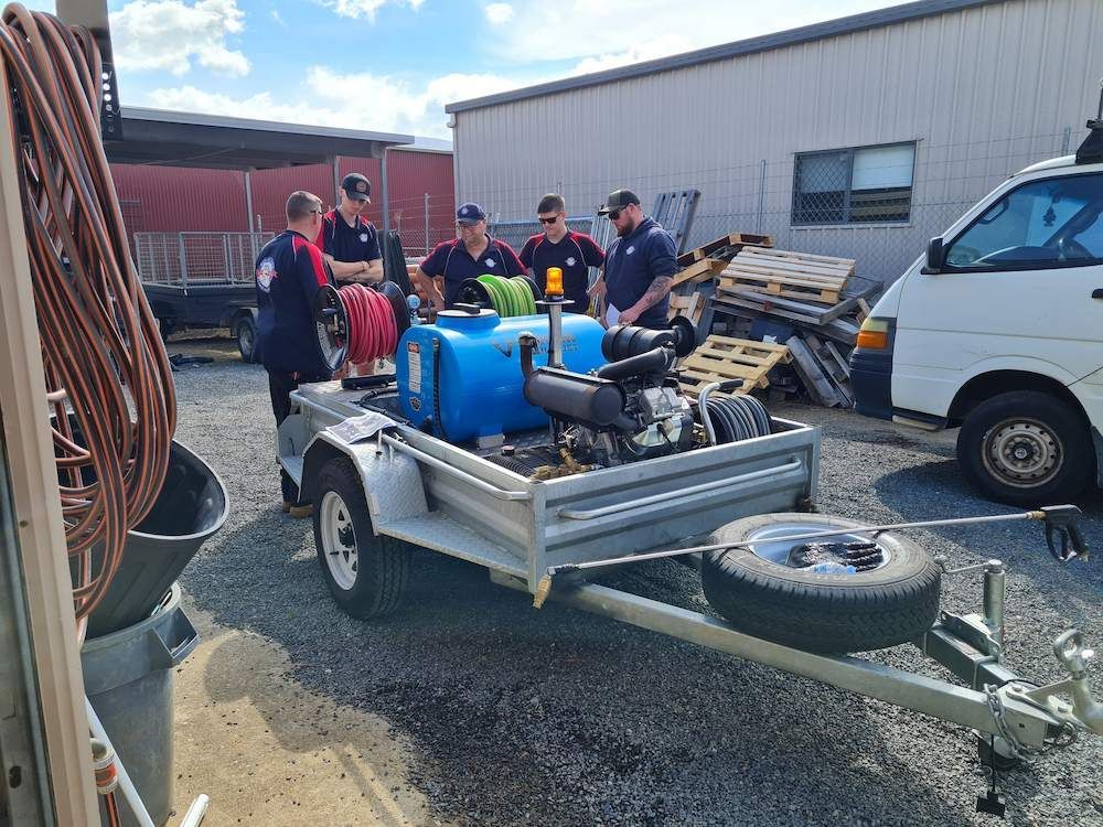 A Group of Men Are Standing Around a Trailer — Around Town Plumbing Services in Woden Valley, ACT