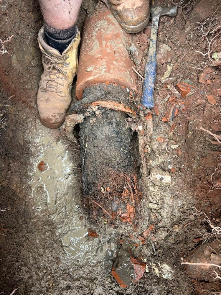 A Person is Standing Next to a Large Pipe in the Dirt — Around Town Plumbing Services in Canberra, ACT