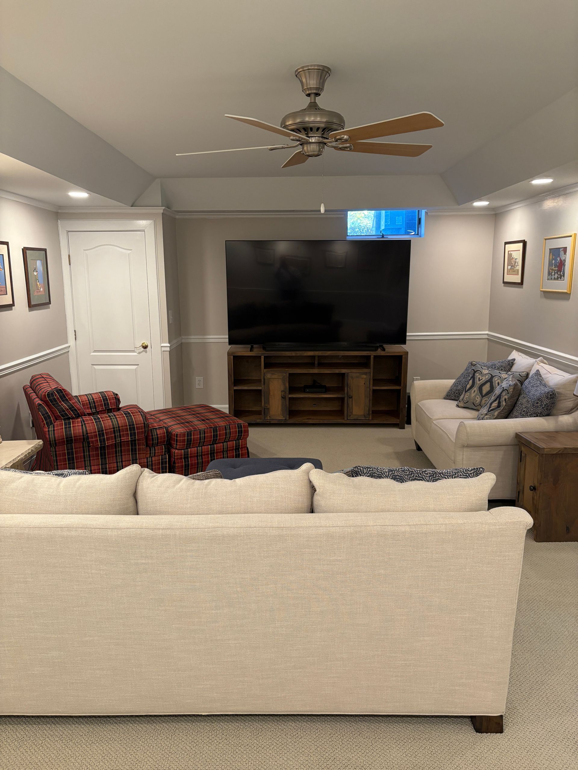 Living room with light sofas, a large TV, and a wooden entertainment center.