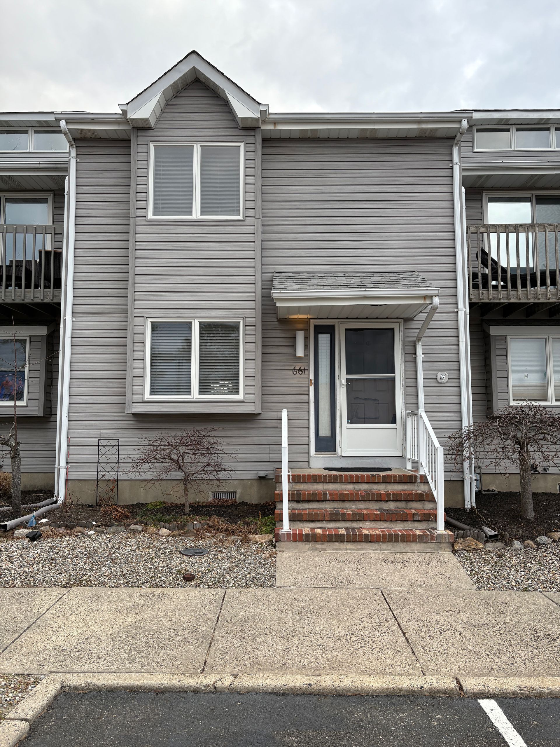 Gray townhome with front steps, door, and windows.