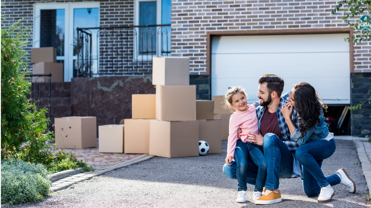 A kitchen with white cabinets , wooden floors , stainless steel appliances and a large island with chairs.
