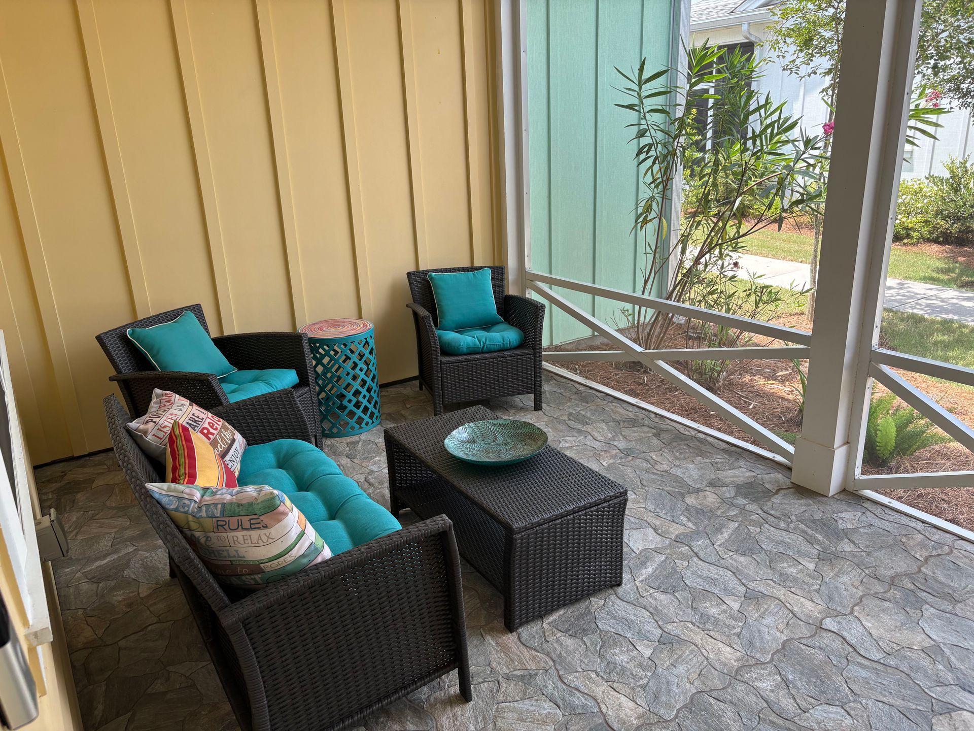 Outdoor seating area with wicker furniture, teal cushions, and a small table.