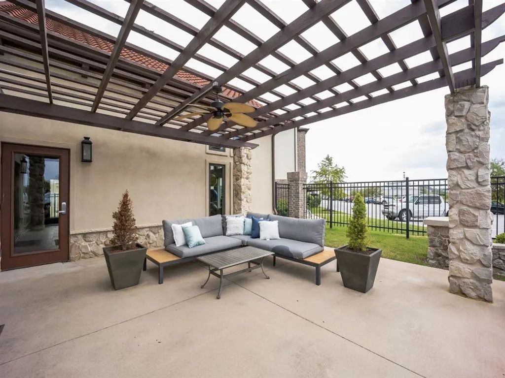 Outdoor patio with a sectional sofa, a pergola, and stone columns.