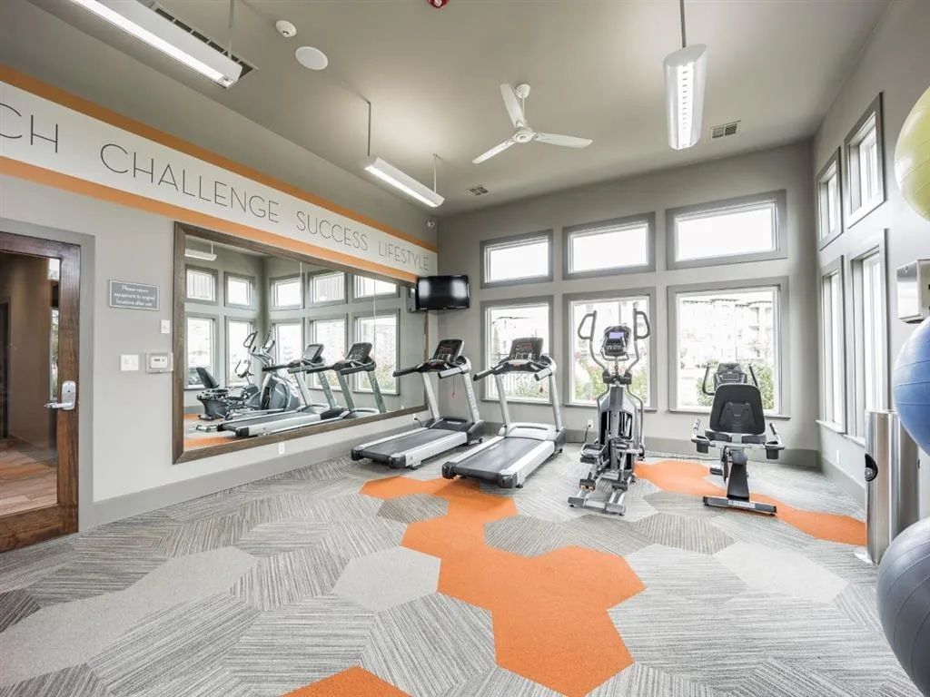 Gym interior with treadmills, elliptical, exercise bike, and weights.