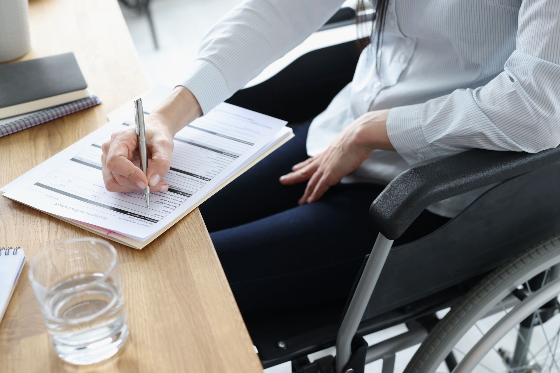 A disabled woman in a wheelchair filling out an application for social security disability.