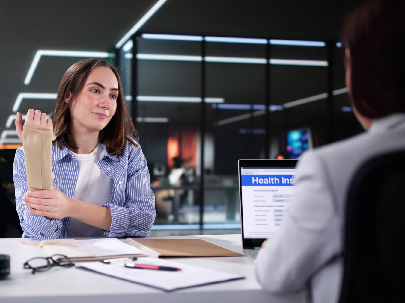 A woman with an injured wrist speaks to a workers comp lawyer to file a claim.