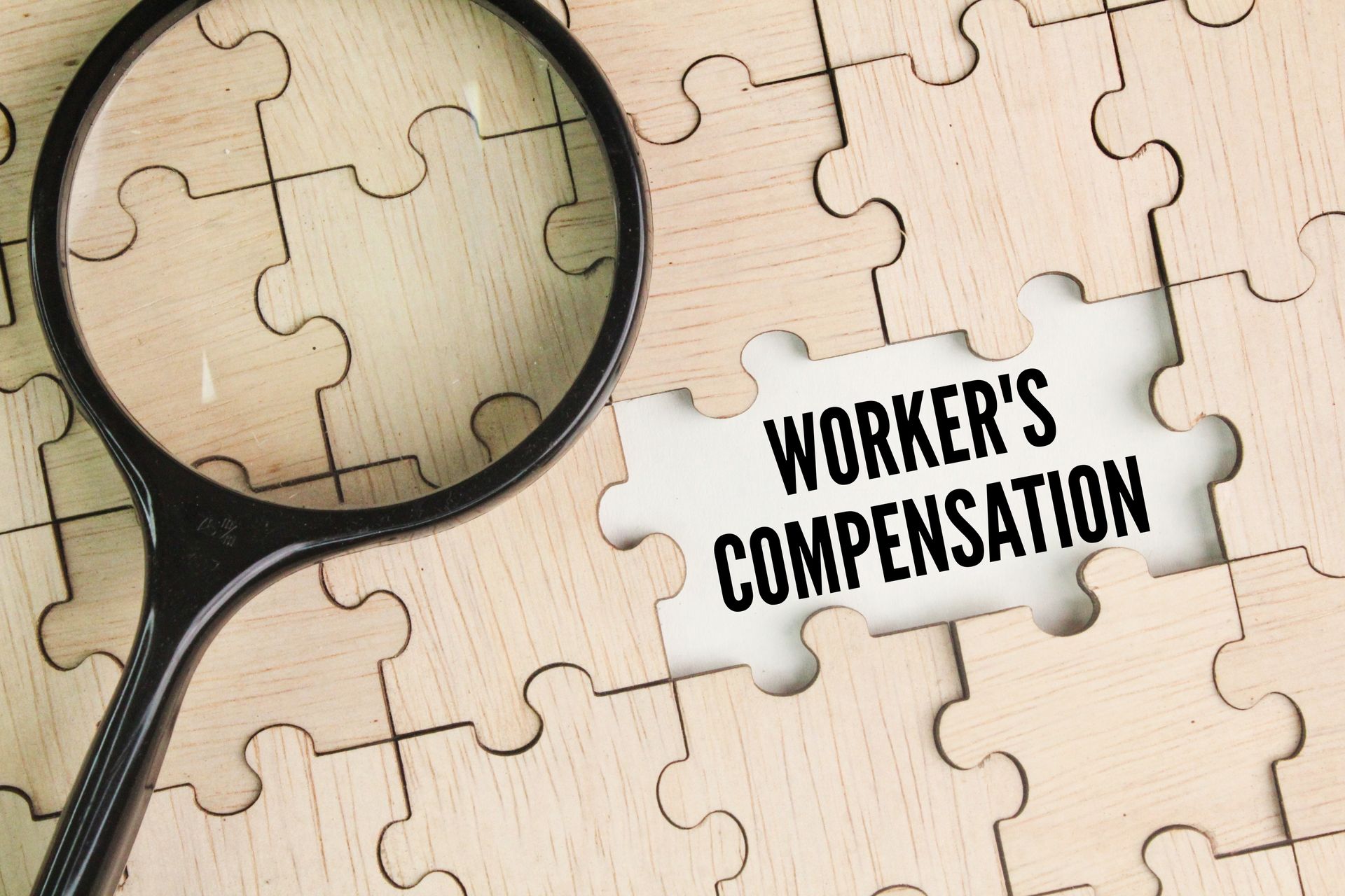 Magnifying glass over puzzle piece showing text 'Worker's Compensation'.