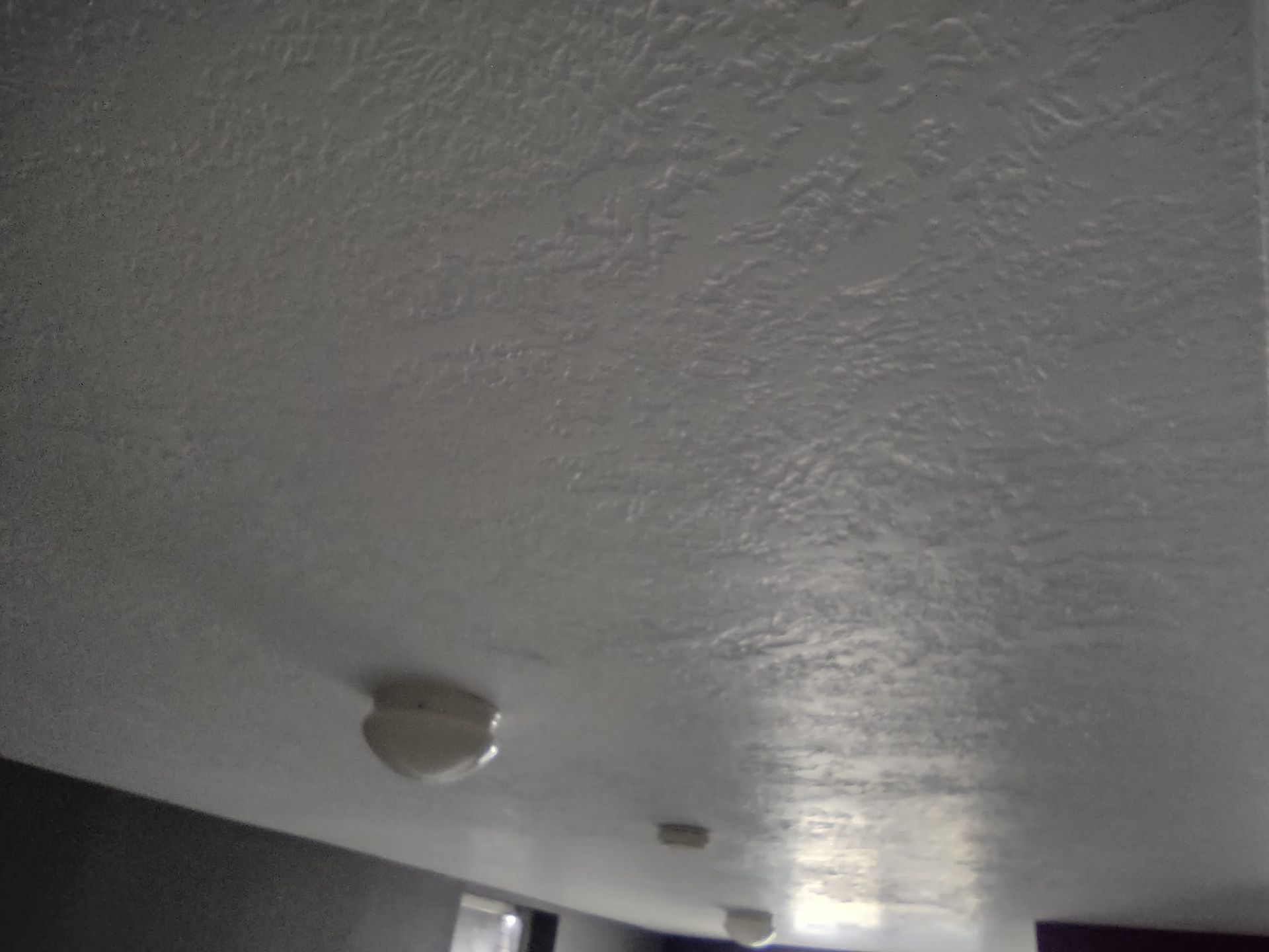 A ceiling with a textured surface and several white smoke detectors.
