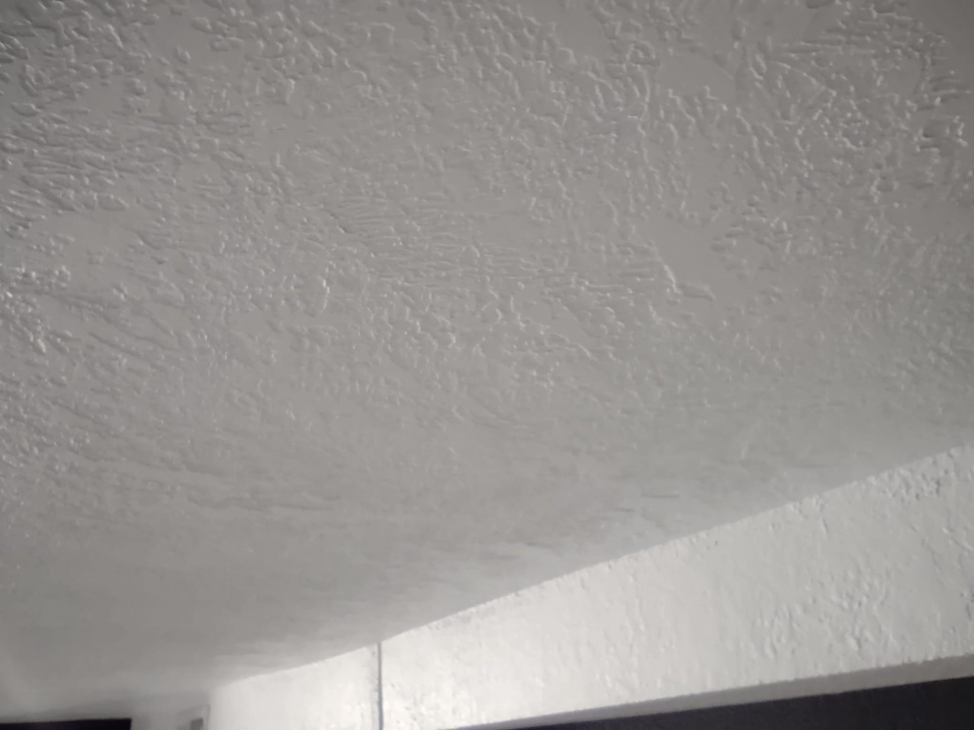 Textured white ceiling, with a white support beam in the lower corner.