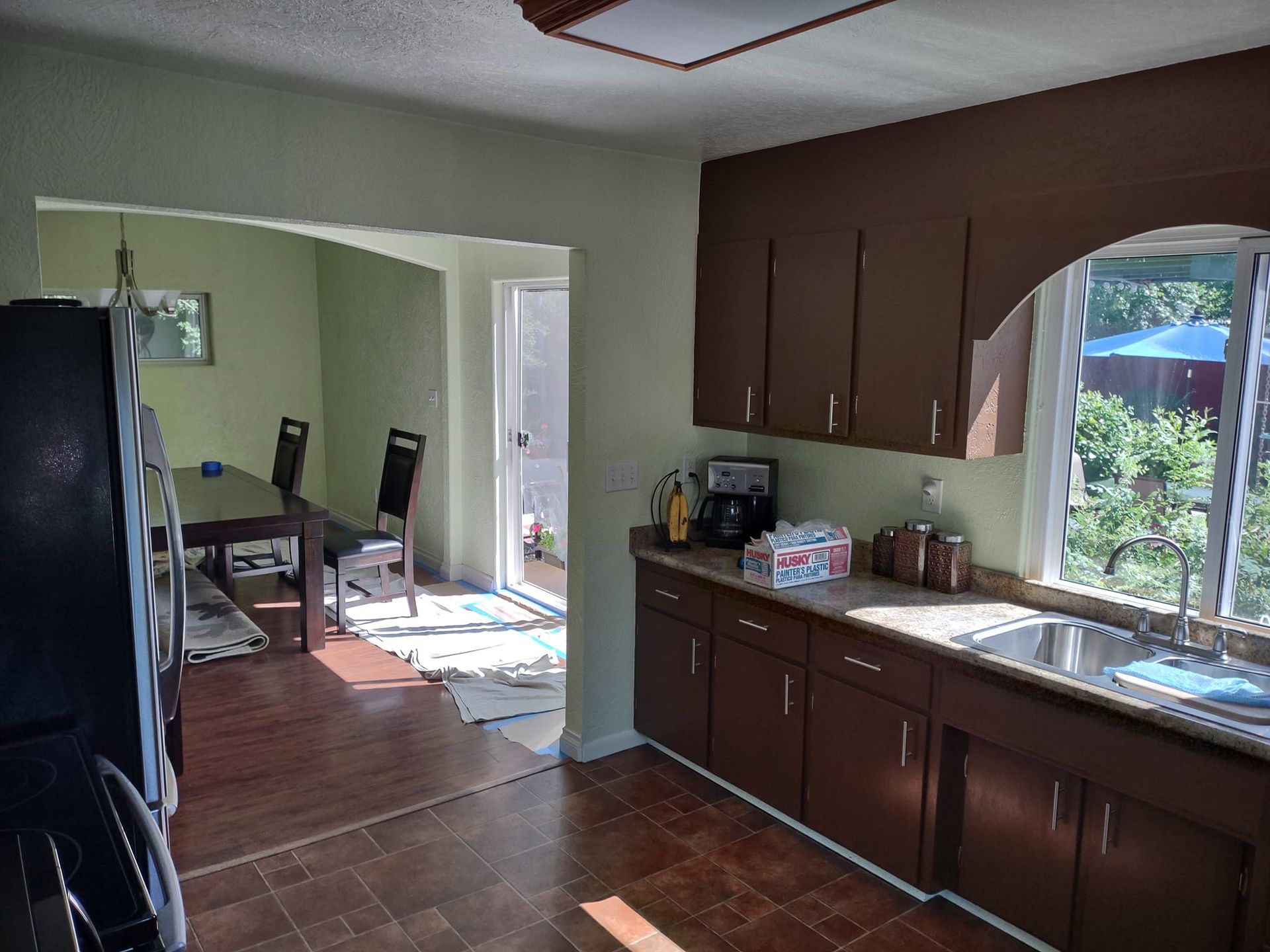Kitchen with brown cabinets, sink, and a view into a dining area with a table and chairs.