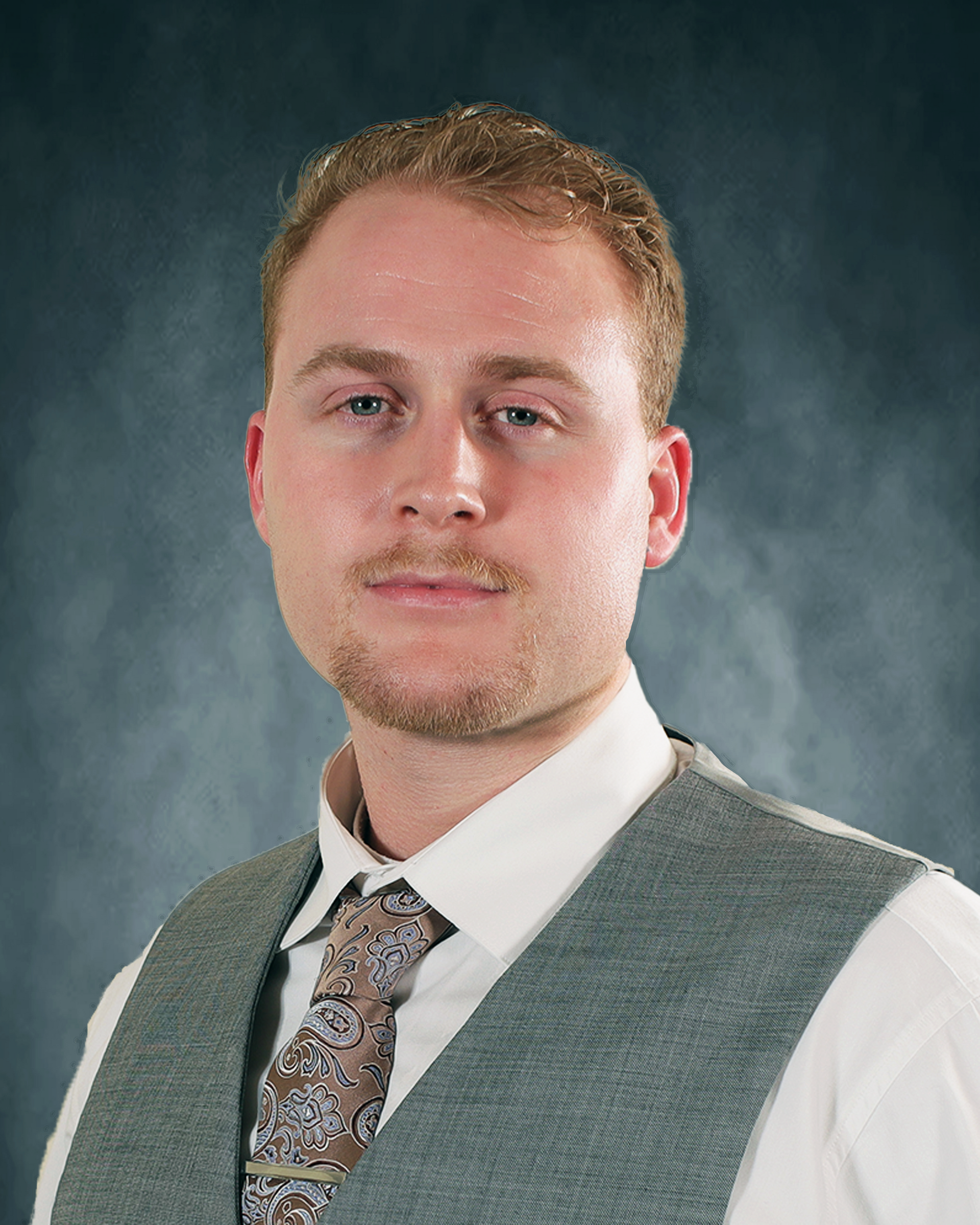 Cade Erwin in a suit and tie is smiling for the camera.