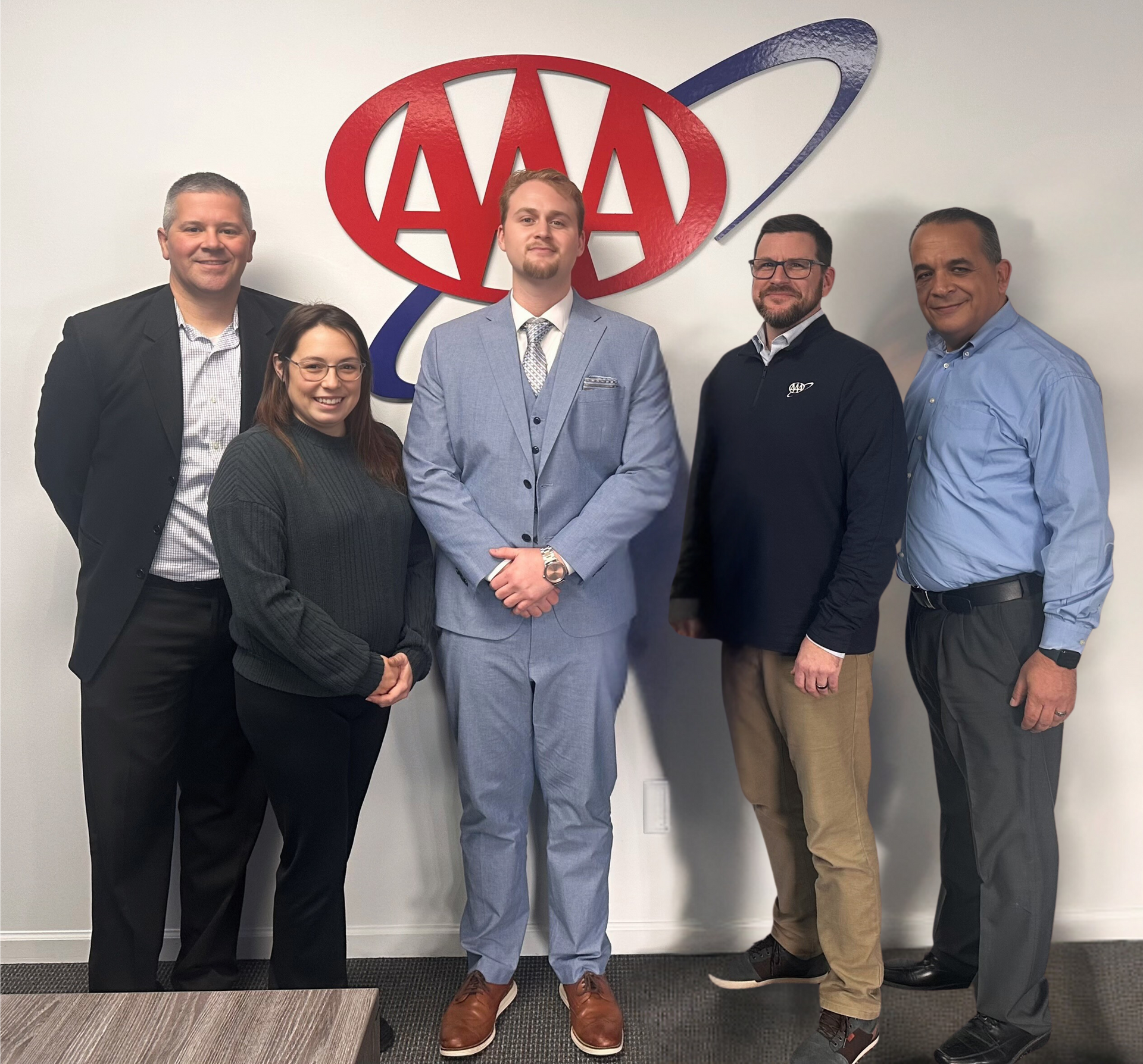 A group of people standing in front of an aaa logo