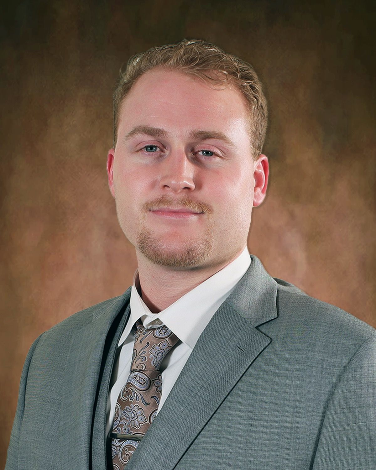 Cade Erwin in a suit and tie is smiling for the camera.