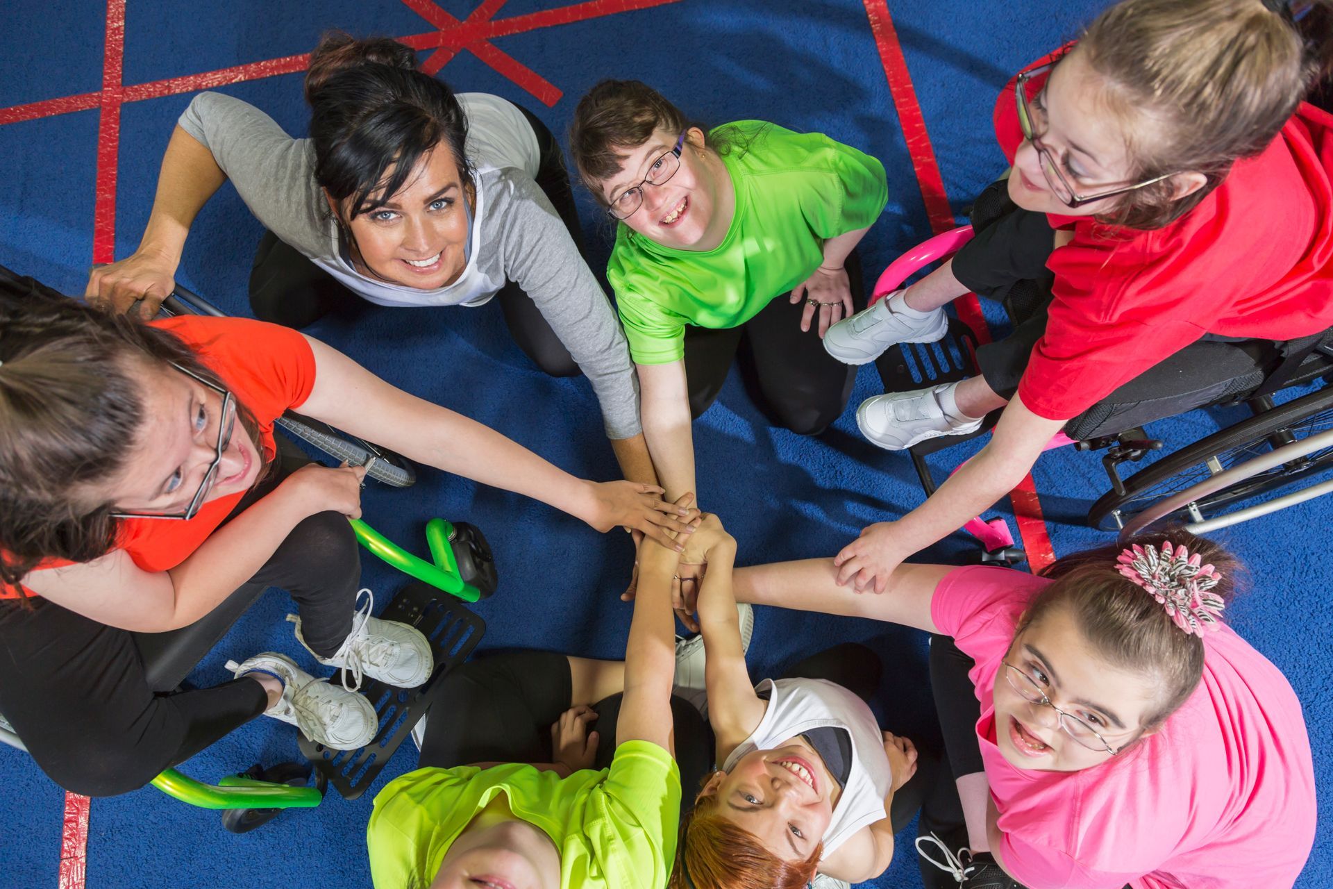 A group of children are putting their hands together in a circle.