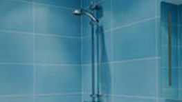 A close up of a shower head in a bathroom with blue tiles.