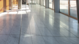 A long hallway with a marble floor and lots of windows.