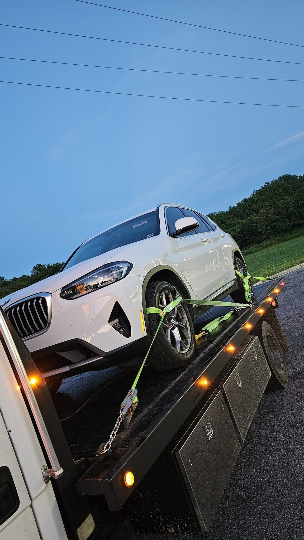 A white car is being towed by a tow truck.