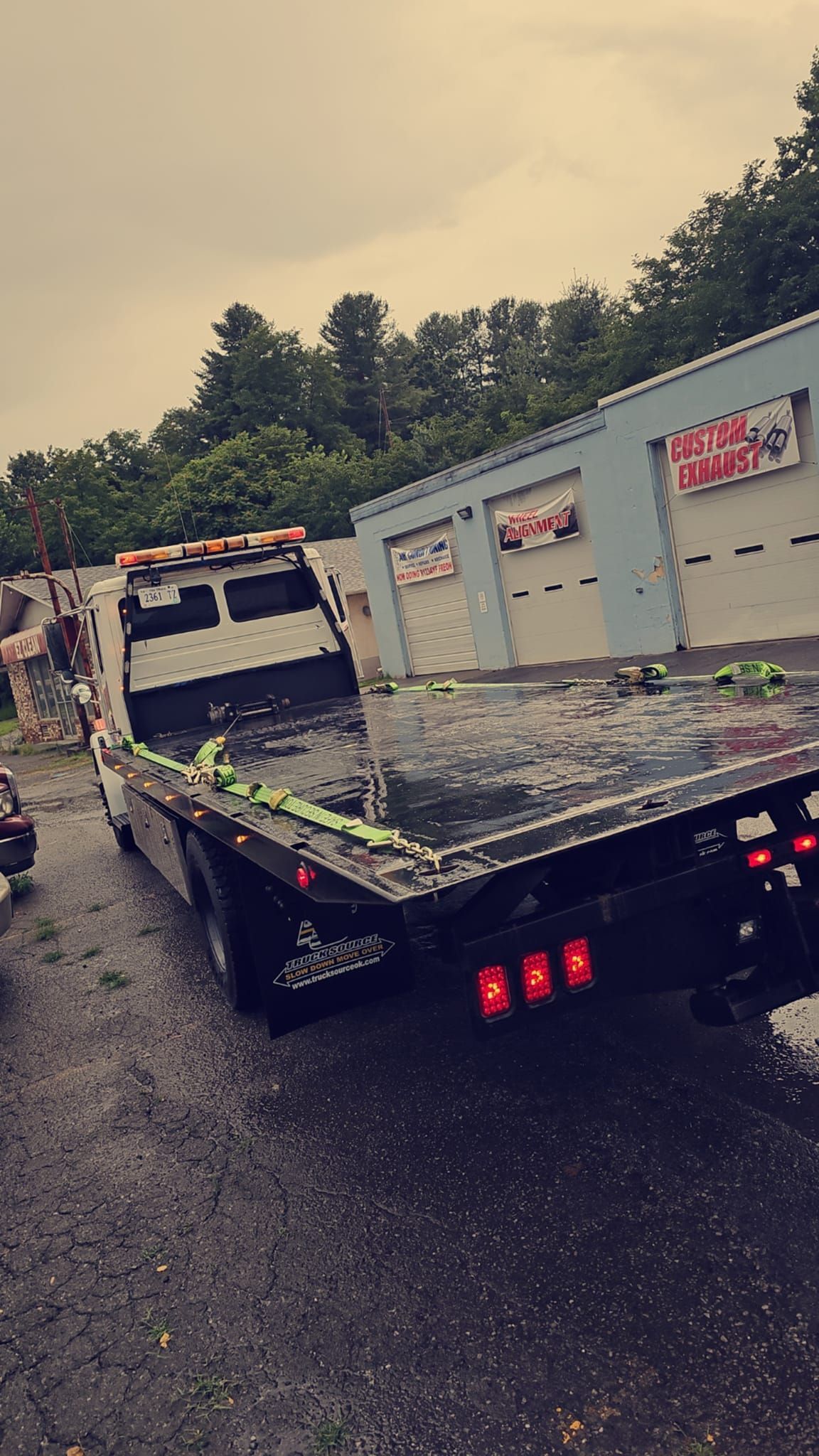 A tow truck is parked in front of a garage.