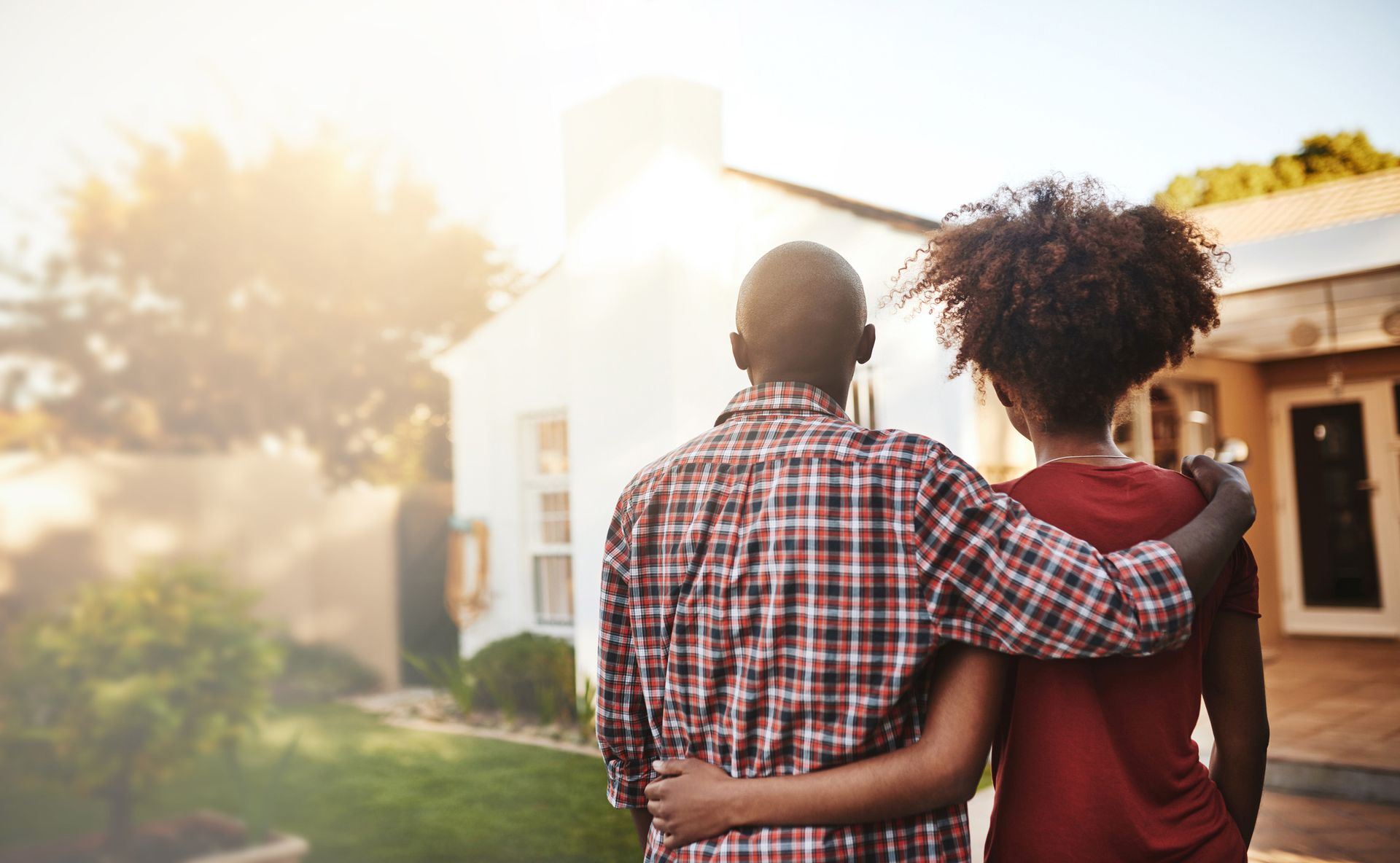 A man and a woman are standing in front of a house.