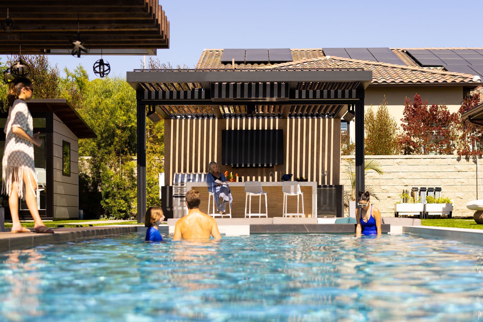 Poolside scene with swimmers and a covered bar area.