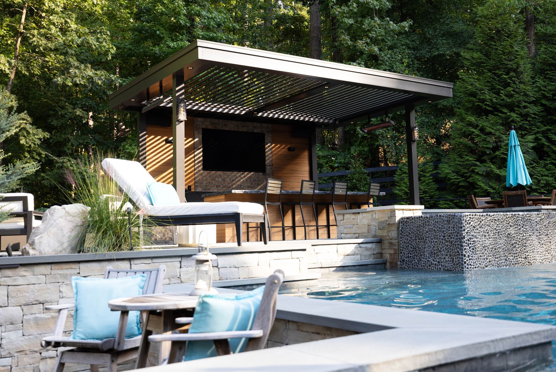 Outdoor bar and lounge area by a pool with seating and pergola.