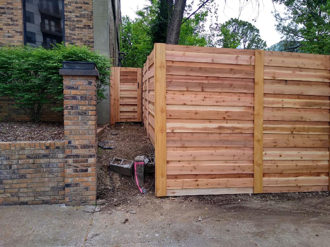 A wooden fence is in front of a brick building. Clarksville, TN