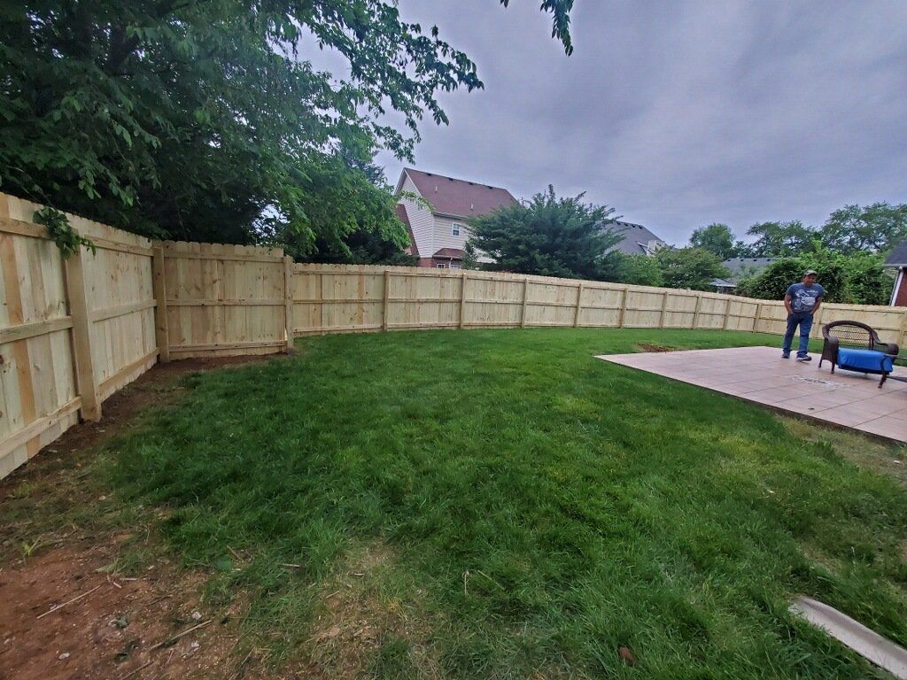 A man is standing in a backyard next to a wooden fence. Clarksville, TN