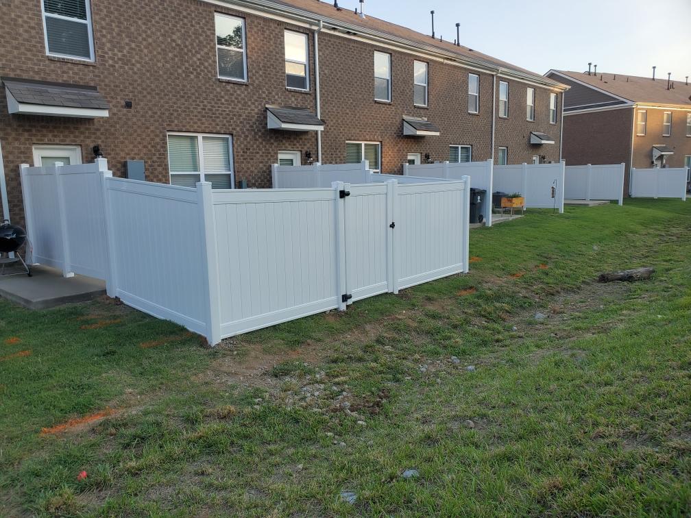 A white fence is in the middle of a grassy field in front of a brick building. Clarksville, TN