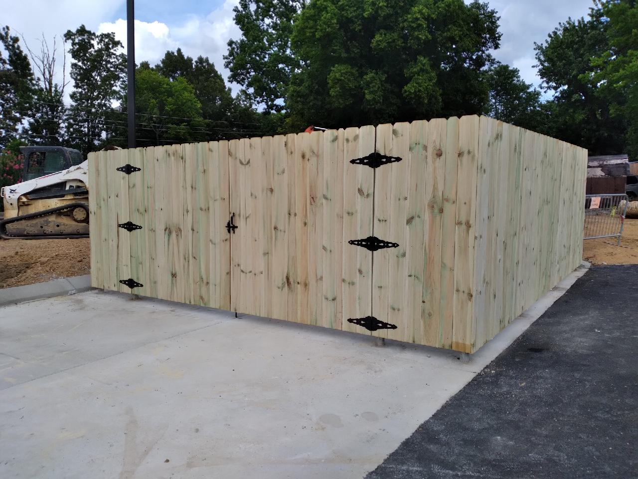 A wooden fence with black hinges is in a parking lot. Clarksville, TN