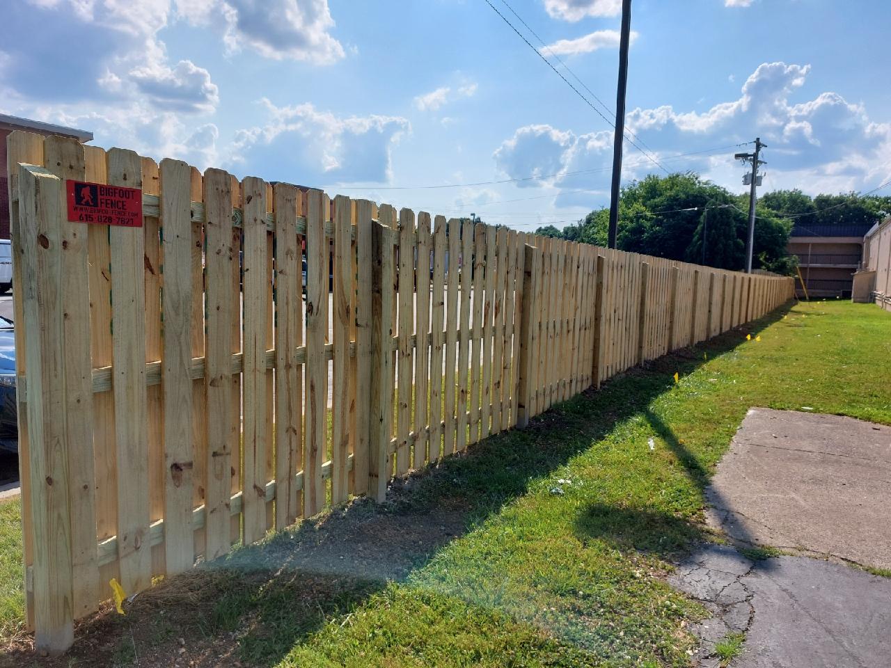 A wooden fence is sitting on the side of the road next to a sidewalk. Clarksville, TN