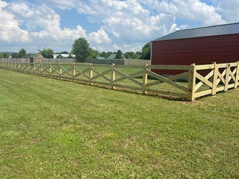A wooden fence surrounds a grassy field with a red barn in the background. Clarksville, TN