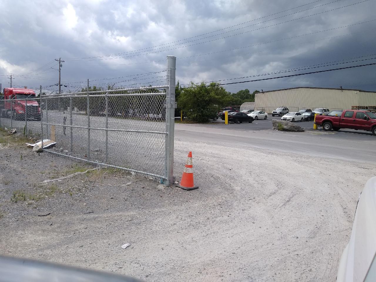 A chain link fence surrounds a parking lot with a red truck in the background. Clarksville, TN