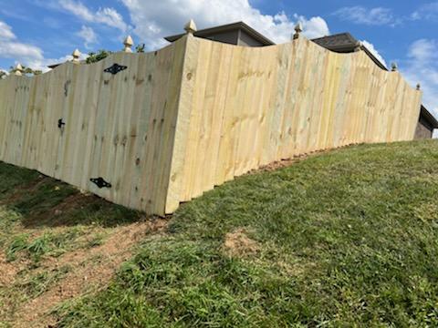 A wooden fence is sitting on top of a grassy hill next to a house.Clarksville, TN
