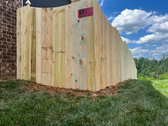 A wooden fence is sitting in the grass next to a brick building. Clarksville, TN